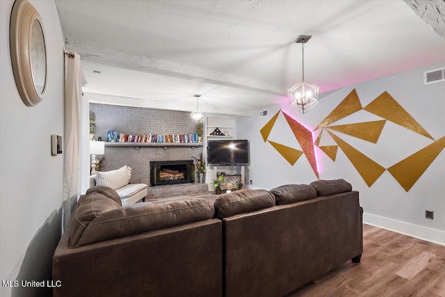 living room featuring beam ceiling, wood-type flooring, and a brick fireplace