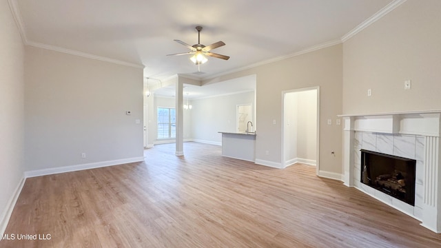 unfurnished living room with sink, crown molding, ceiling fan, light hardwood / wood-style floors, and a tiled fireplace