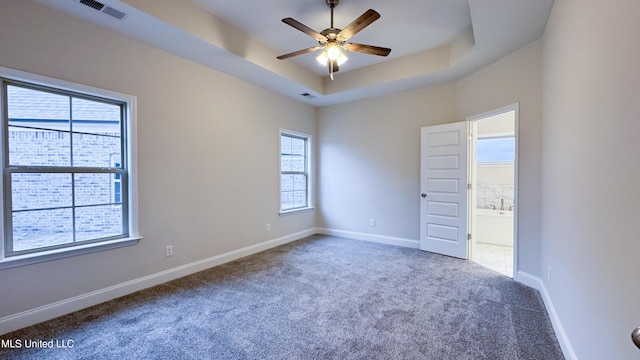 carpeted empty room featuring a tray ceiling and ceiling fan