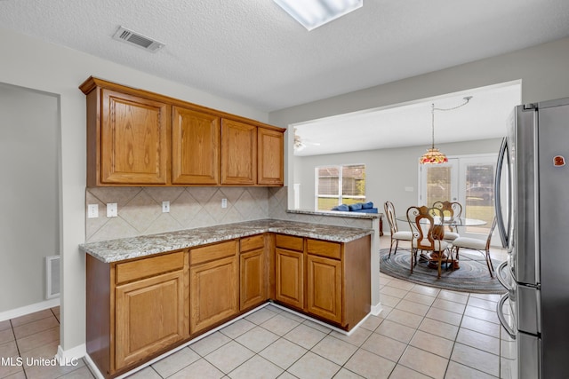 20 Lakeview Dr, Ocean Springs, MS 39564 - kitchen with freestanding refrigerator, backsplash, light tile patterned flooring, and brown cabinetry