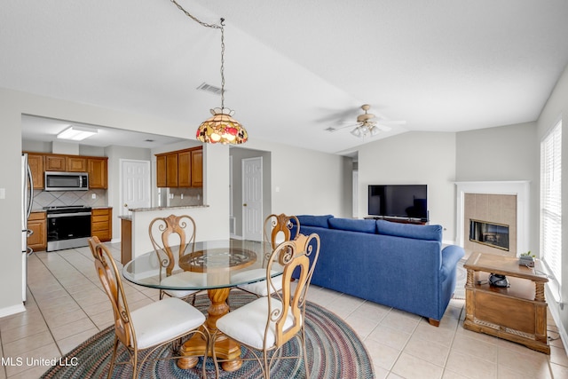 20 Lakeview Dr, Ocean Springs, MS 39564 - dining space with light tile patterned floors, a ceiling fan, lofted ceiling, and a tile fireplace