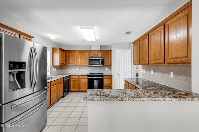 20 Lakeview Dr, Ocean Springs, MS 39564 - kitchen featuring appliances with stainless steel finishes, backsplash, a peninsula, brown cabinets, and light stone countertops