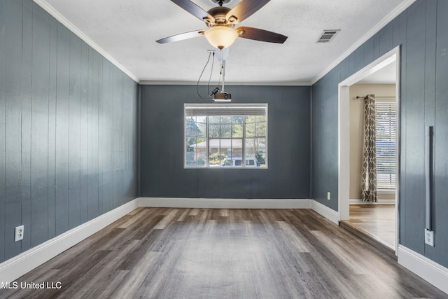 empty room with a textured ceiling, wood-type flooring, ornamental molding, and a healthy amount of sunlight