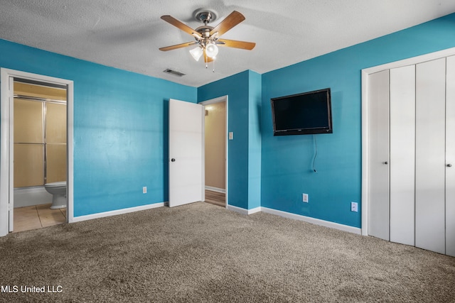 unfurnished bedroom featuring ceiling fan, carpet flooring, ensuite bath, and a closet