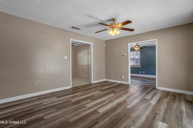 empty room with ceiling fan, dark wood-type flooring, and a textured ceiling