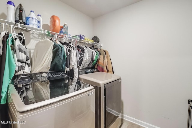 washroom with washing machine and clothes dryer and hardwood / wood-style flooring