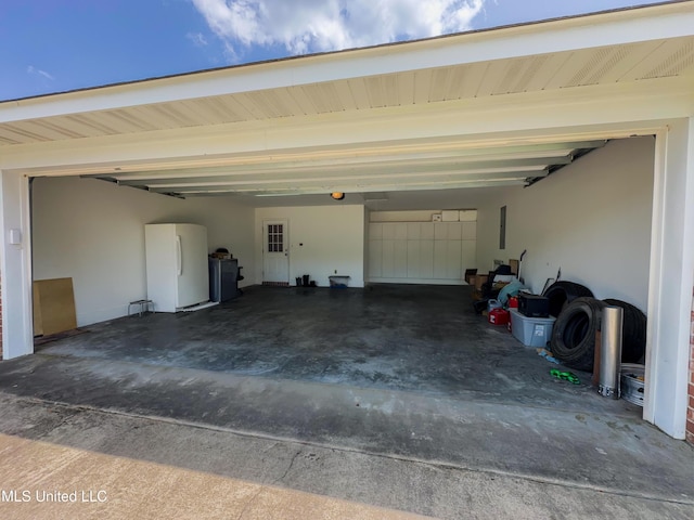1104 SE 2nd St, Magee, MS 39111 - garage featuring freestanding refrigerator, concrete driveway, and electric panel