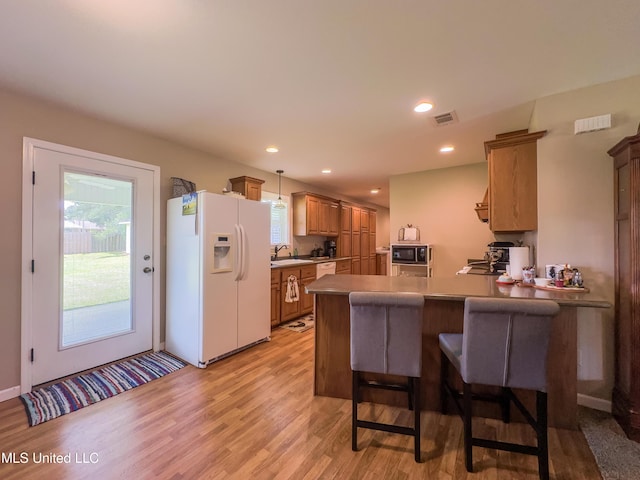1104 SE 2nd St, Magee, MS 39111 - kitchen with white appliances, light wood-style floors, a peninsula, a sink, and a kitchen bar