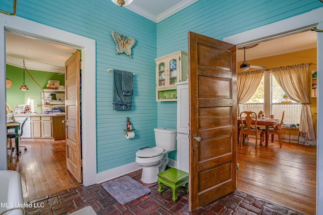 3508 11th St, Gulfport, MS 39501 - bathroom featuring ornamental molding, toilet, ceiling fan, wooden walls, and brick patterned floors