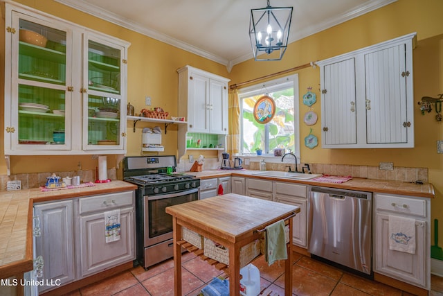 kitchen with white cabinets, appliances with stainless steel finishes, sink, tile counters, and decorative light fixtures