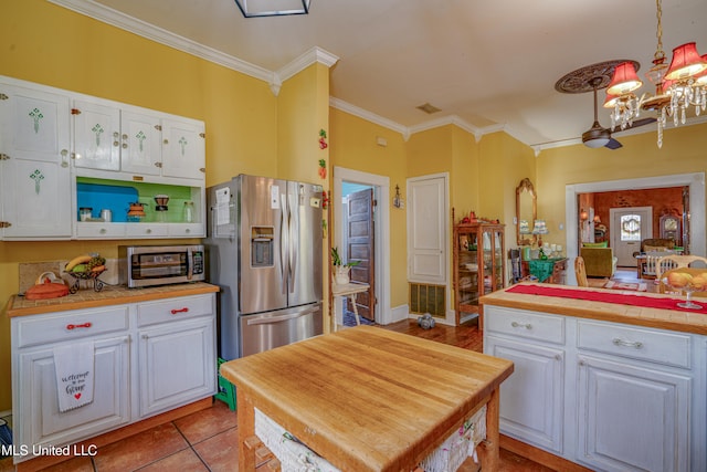 kitchen featuring white cabinets, appliances with stainless steel finishes, an inviting chandelier, and hanging light fixtures