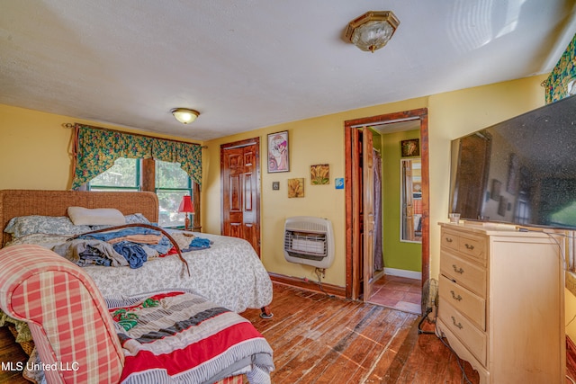 bedroom with wood-type flooring and heating unit