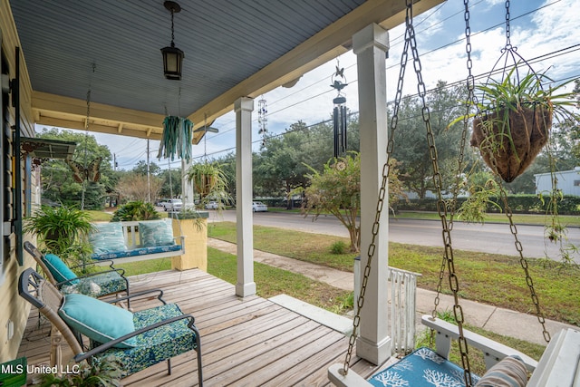 wooden terrace featuring a porch and a lawn