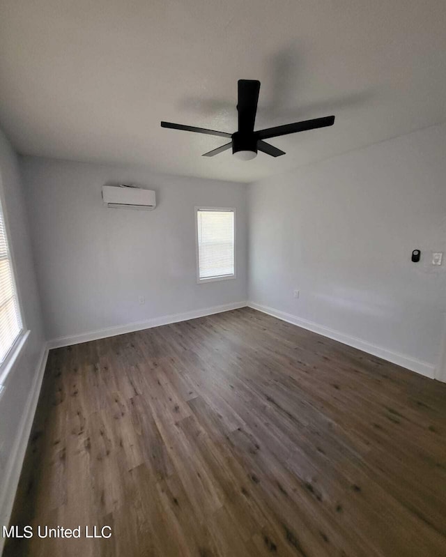 empty room featuring a wall unit AC, dark wood-type flooring, and ceiling fan