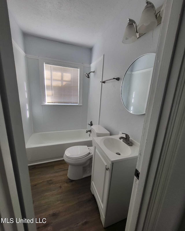 full bathroom with shower / washtub combination, a textured ceiling, hardwood / wood-style floors, toilet, and vanity