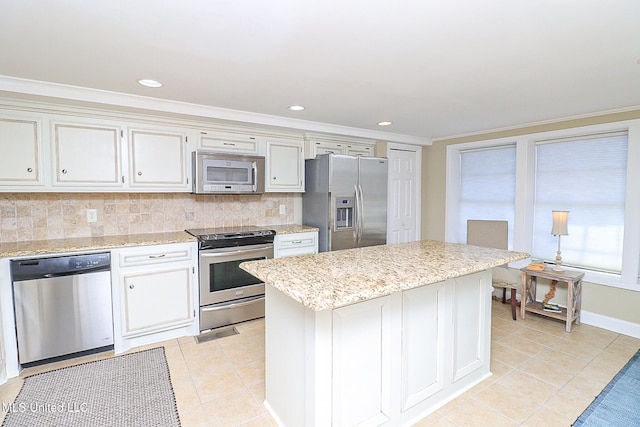 kitchen with decorative backsplash, a kitchen island, ornamental molding, and stainless steel appliances