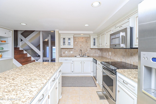 kitchen with light stone countertops, sink, decorative backsplash, light tile patterned floors, and appliances with stainless steel finishes