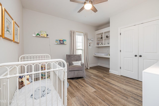 bedroom with hardwood / wood-style flooring, built in desk, ceiling fan, and a closet