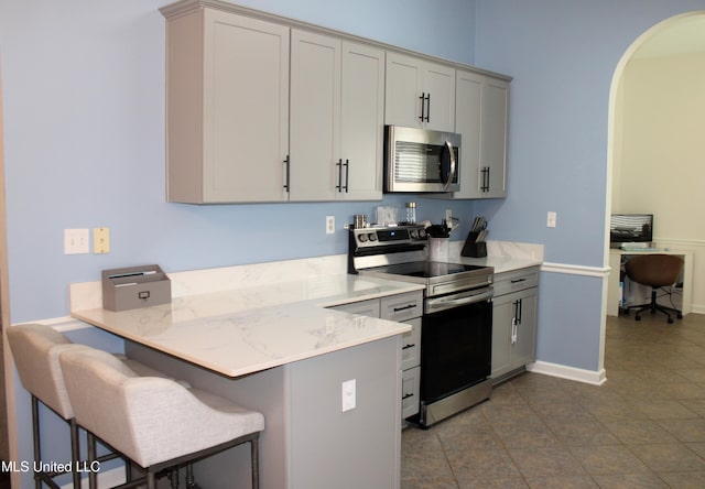 6904 Braybourne Main, Olive Branch, MS 38654 - kitchen featuring stainless steel appliances, a kitchen breakfast bar, a peninsula, arched walkways, and a desk