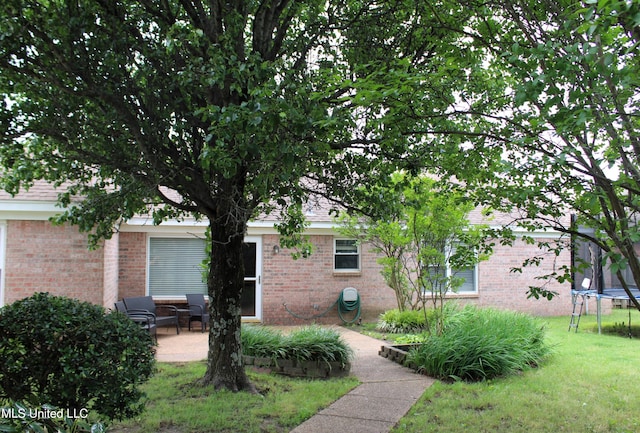 6904 Braybourne Main, Olive Branch, MS 38654 - exterior space with a trampoline, brick siding, a patio area, and a yard
