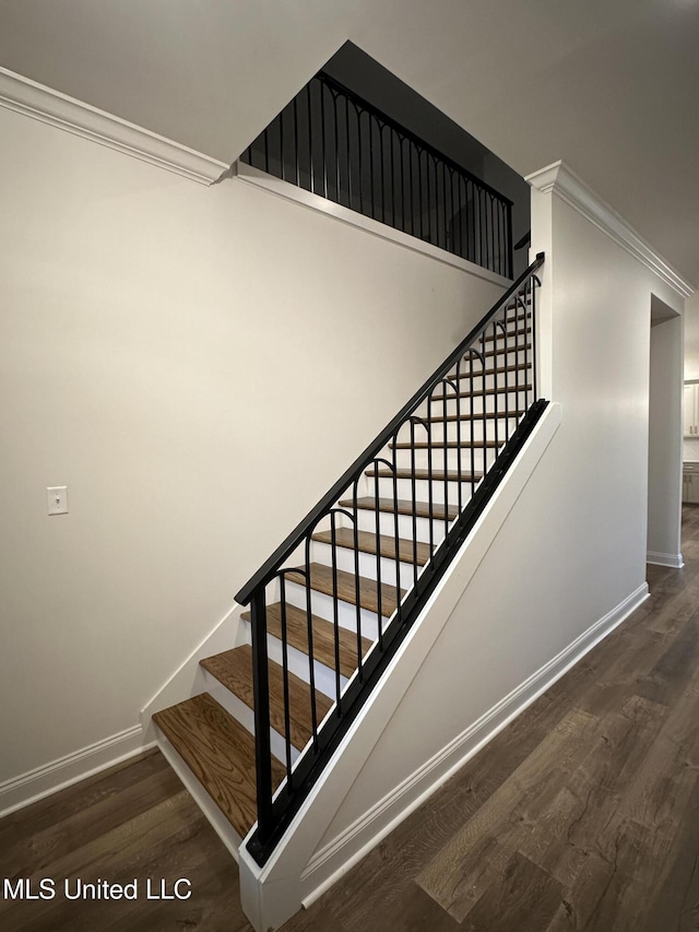 stairway with baseboards, wood finished floors, and crown molding