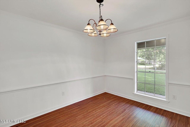 empty room featuring a notable chandelier, a healthy amount of sunlight, ornamental molding, and hardwood / wood-style floors