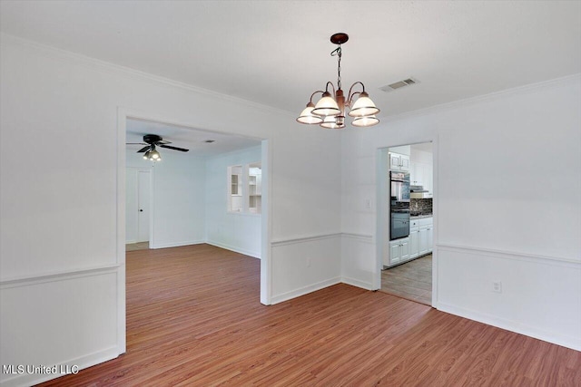 unfurnished dining area featuring ornamental molding, ceiling fan with notable chandelier, and light wood-type flooring