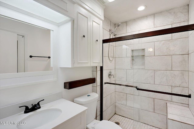 bathroom with toilet, vanity, and tiled shower