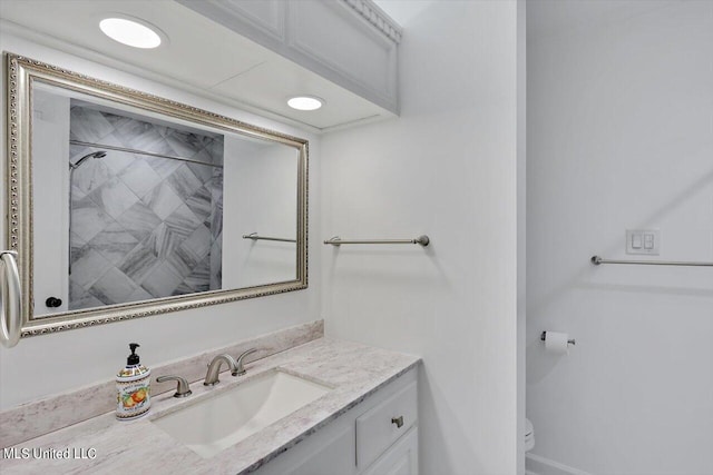 bathroom with vanity, toilet, and tiled shower