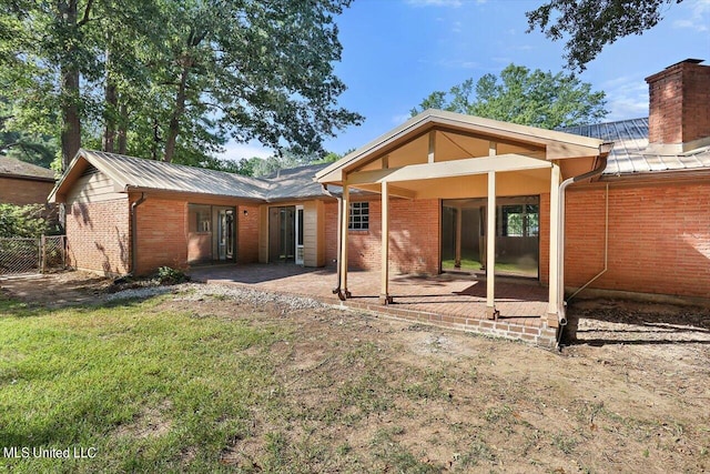 back of property with a patio area and a lawn