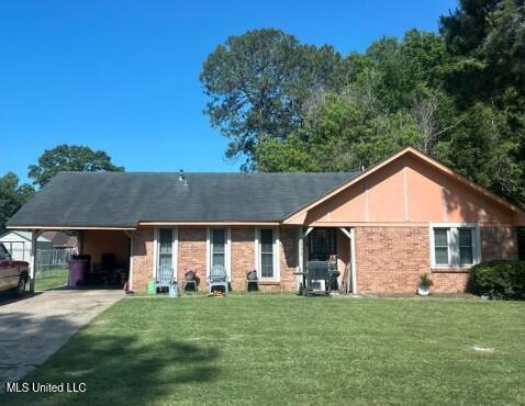6513 Abraham Lincoln Dr, Jackson, MS 39213 - view of front of home with a front lawn, concrete driveway, brick siding, and an attached carport