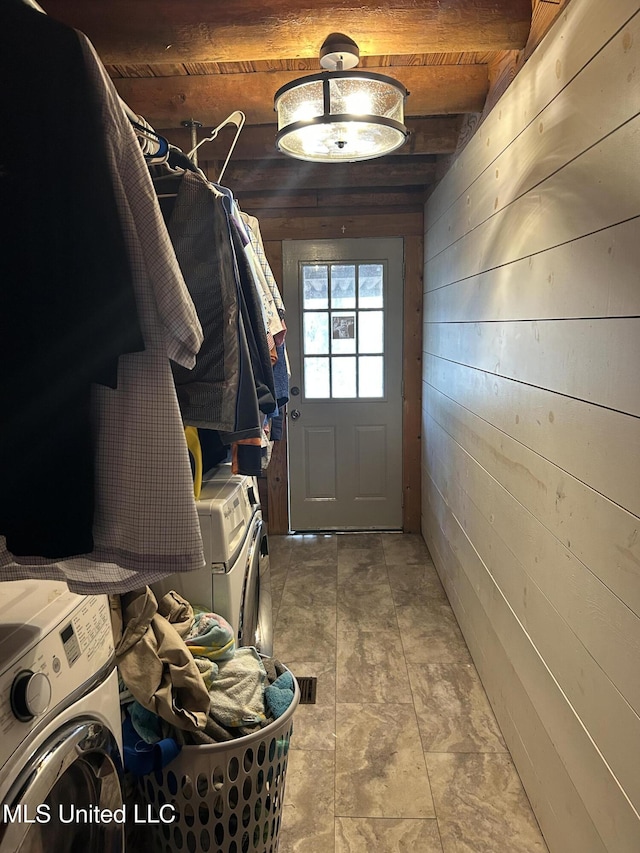 mudroom featuring beam ceiling, washing machine and dryer, and wooden walls