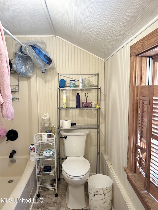 bathroom featuring lofted ceiling, tile patterned flooring, toilet, and tub / shower combination