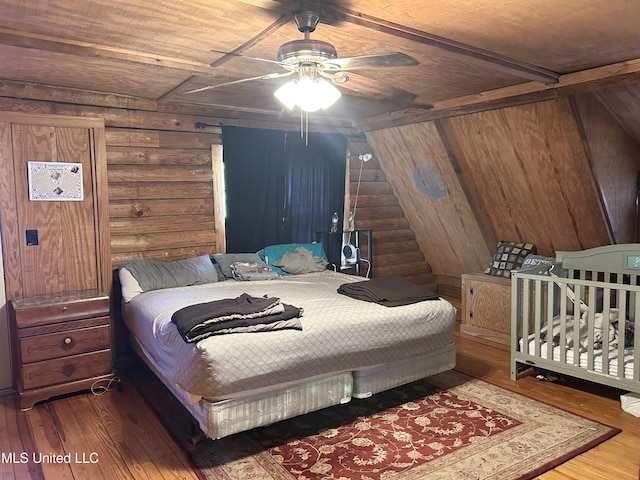 bedroom featuring wood-type flooring, rustic walls, ceiling fan, and wood ceiling