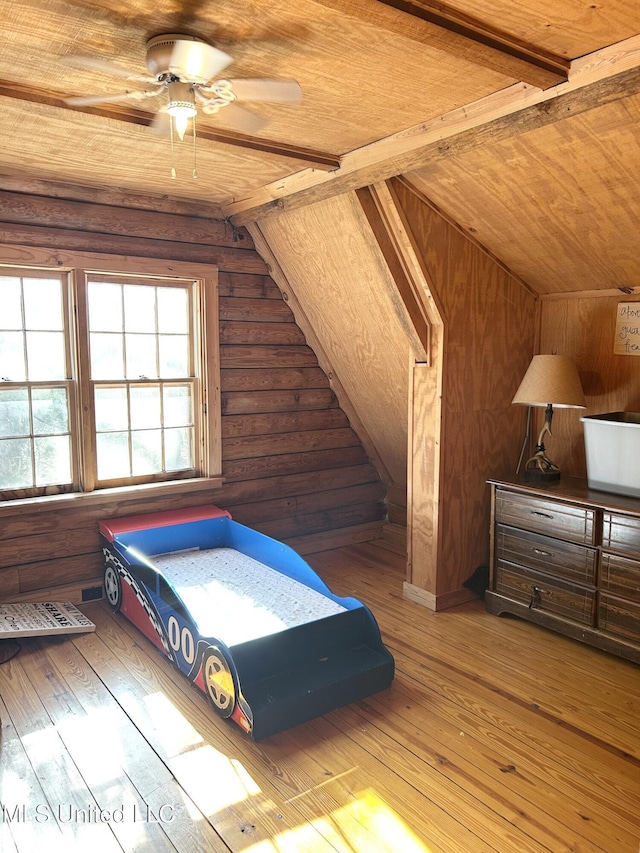 unfurnished bedroom featuring wooden walls, hardwood / wood-style floors, and vaulted ceiling with beams