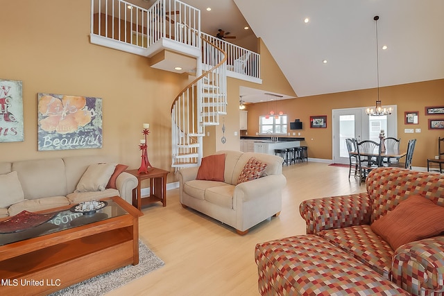 living room featuring a towering ceiling, light hardwood / wood-style flooring, and ceiling fan with notable chandelier