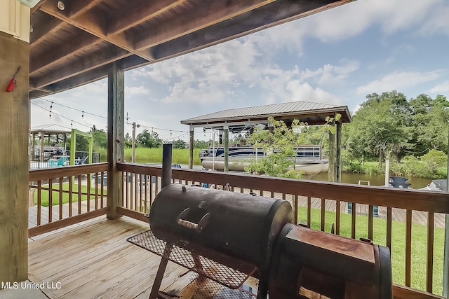 deck with grilling area, a gazebo, a yard, and a water view