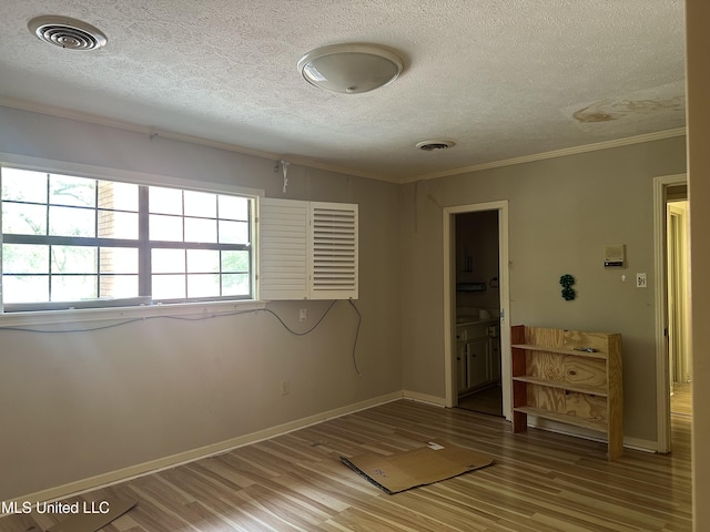 25 Oak Creek Pl, Jackson, MS 39211 - unfurnished bedroom featuring a textured ceiling, light wood finished floors, crown molding, and connected bathroom