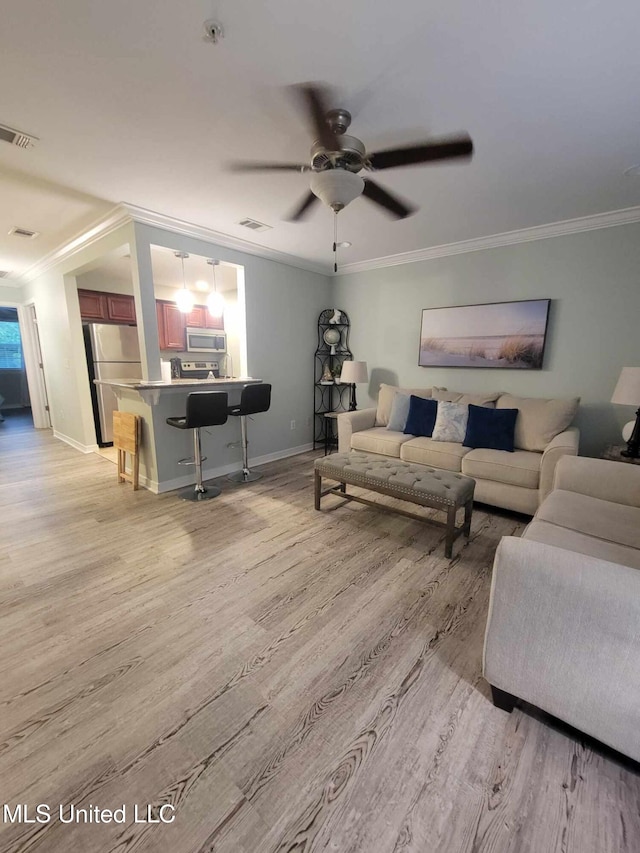 living area featuring ceiling fan, ornamental molding, light wood-type flooring, and visible vents