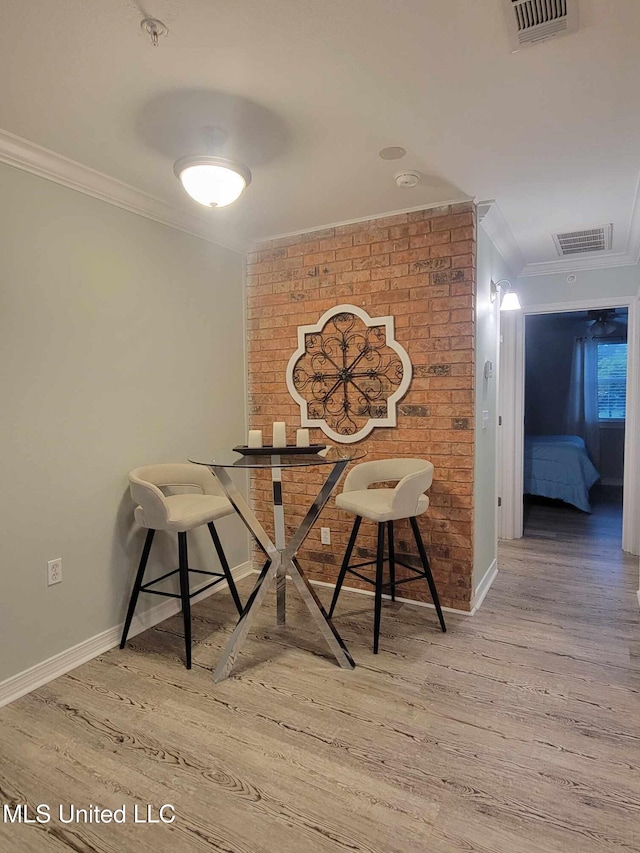 dining space featuring visible vents, wood finished floors, baseboards, and ornamental molding
