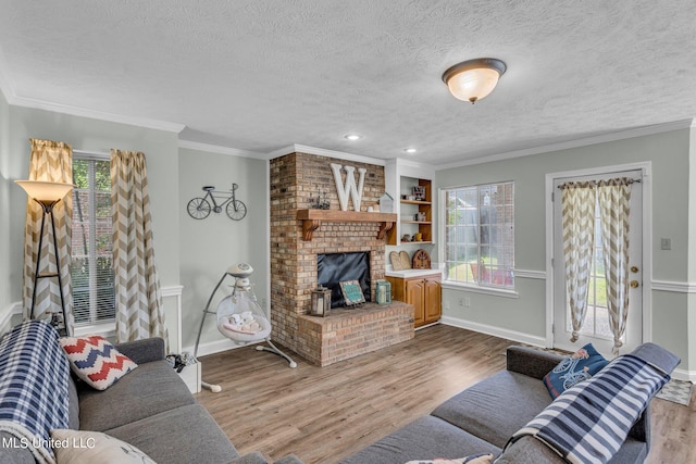 living room with hardwood / wood-style flooring, ornamental molding, a textured ceiling, and a brick fireplace