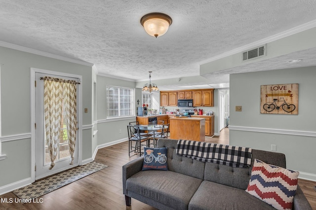 living room featuring hardwood / wood-style floors, a textured ceiling, crown molding, and a healthy amount of sunlight