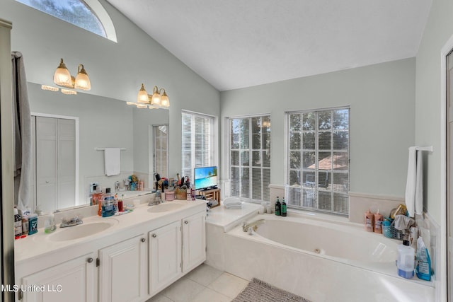 bathroom with vanity, tiled bath, vaulted ceiling, and plenty of natural light