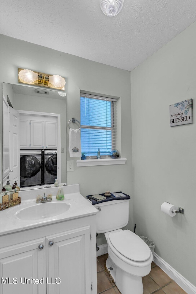 bathroom with washer and clothes dryer, toilet, tile patterned flooring, vanity, and a textured ceiling