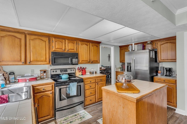 kitchen featuring a center island, stainless steel appliances, tile counters, and light wood-type flooring