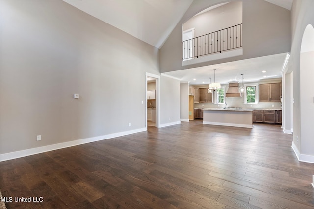 8025 Old Addison Dr, Olive Branch, MS 38654 - unfurnished living room with dark wood-style floors, high vaulted ceiling, baseboards, and a sink