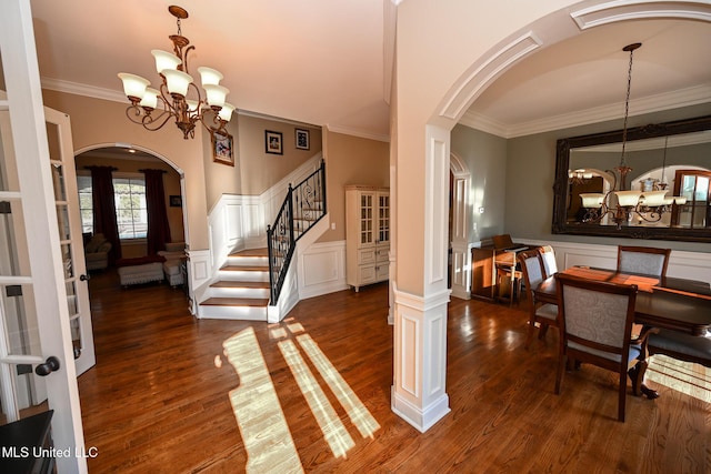 entryway with crown molding, dark hardwood / wood-style flooring, and a notable chandelier