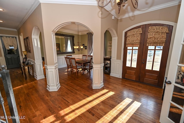 foyer entrance featuring crown molding, dark hardwood / wood-style floors, a chandelier, and french doors