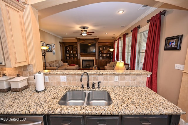 kitchen featuring light stone counters, ornamental molding, sink, and cream cabinetry