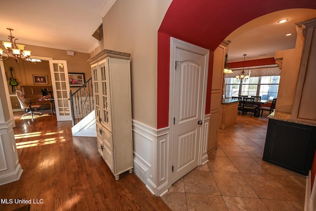 corridor with crown molding, a chandelier, and dark tile patterned floors